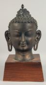 A BURMESE BRONZE HEAD 16ins high on a wooden base.