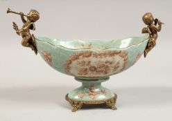 AN OVAL PORCELAIN BOWL with gilt cherubs handles and base. 11ins wide.