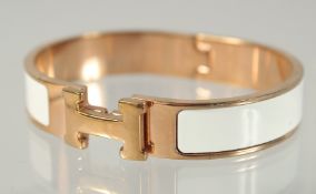 A HERMES WHITE AND GILT BANGLE.