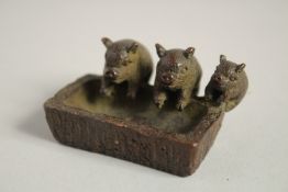 THREE BRONZE PIGS at a trough. 2ins long.
