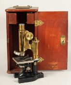 A BAUSCH & LOMB OPT CO., ROCHESTER, NEW YORK. BLACK AND BRASS MICROSCOPE. 11ins high in a mahogany