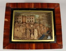 A FRAMED AND GLAZED CORK PICTURE, building on rocks, it lights up. 9.5ins x 12ins.