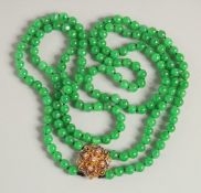 A VERY GOOD TWO STRAND JADE NECKLACE with gold and diamond clasp.