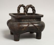 A CHINESE BRONZE SQUARE CENSER with rope handles on four curving legs, the sides with calligraphy.