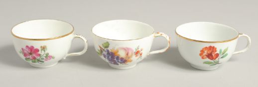 THREE 19TH CENTURY BERLIN PORCELAIN CUPS painted with flowers. Sceptre mark in blue.