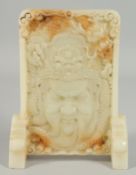 A CHINESE JADE SCREEN AND STAND carved with a mask. 9ins high