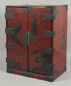 A JAPANESE RED LACQUERED TWO DOOR CABINET. 19ins high.
