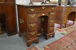 A George III mahogany kneehole desk with one long drawer over a secret drawer, cupboard door flanked