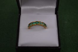 An 18 carat gold and emerald 7 stone eternity ring.