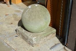 A large composite weathered garden orb on square base.
