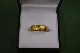 An 18 carat gold textured wedding band.