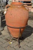 A large continental terracotta twin handled urn with wrought iron stand.