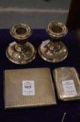 Two silver cigarette cases and a pair of silver dwarf candlesticks.