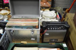 An aluminium case containing LP records together with a mini amplifier.
