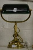 A brass desk lamp with a green glass shade.