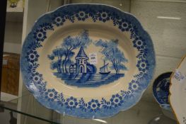 A blue and white oval dish painted with a building and ship.