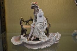 A Dresden porcelain group of a young lady seated on a bench.