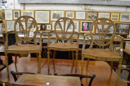 A set of three Hepplewhite style carved and painted beech wood armchairs with canework seats.