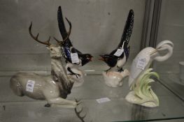 A porcelain recumbent deer, two magpies and a wading bird.