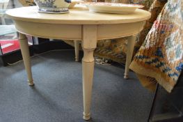 A cream painted French style extending dining table with rounded ends and two leaves on turned