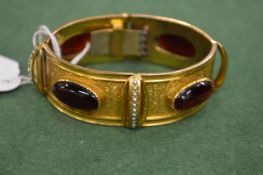 A Victorian gold plated flexible bracelet set with red stones.