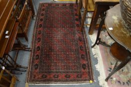 A Persian rug, red ground with stylised decoration 177cm x 90cm.