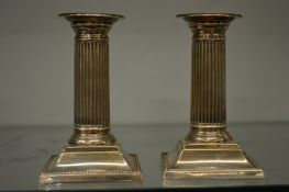 A pair of silver column shaped candlesticks.
