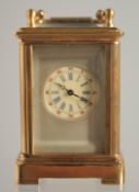 A MINIATURE GILT FACED CARRIAGE CLOCK. 2ins.