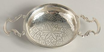 A GEORGE II SILVER TWO HANDLED CIRCULAR LEMON STRAINER. 3.75ins diameter. London 1755. Maker James