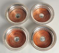 A SET OF FOUR SILVER PLATED CIRCULAR WINE COASTERS with turned down bases.