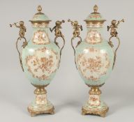 A GOOD PAIR OF FRENCH STYLE PORCELAIN AND METAL URNS AND COVERS with cupid handles. 1ft 8ins high.