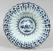 A 19TH CENTURY BLUE AND WHITE RIBBED CHARGER with Chinese design. 13ins diameter.