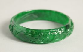 A CARVED JADE BANGLE. 2.25ins diameter.