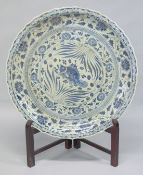 A VERY LARGE CHINESE MING STYLE BLUE AND WHITE PLATTER on a wooden stand. 3ft diameter.