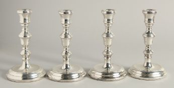 A SET OF FOUR SILVER GEORGIAN STYLE CANDLESTICKS with circular loaded bases. 6.5ins high.