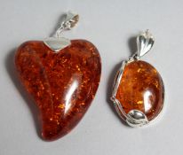 TWO SILVER AND AMBER PENDANTS.
