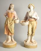 A LARGE PAIR OF ROYAL DUX FIGURES OF A GARDENER AND WIFE both carrying baskets, on circular bases.