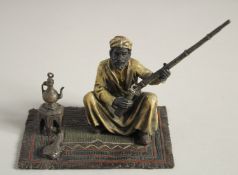 A COLD CAST MODEL OF A MAN holding a gun and sitting on a carpet. 5ins high.