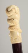 A CARVED BONE HANDLE WALKING STICK, ENTWINED SNAKE. 3ft long.