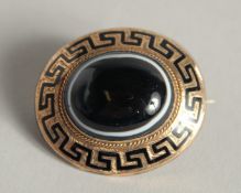 A VICTORIAN GOLD AND BLUE ENAMEL CIRCULAR BROOCH with key pattern decoration and with a single agate