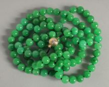 A GOOD STRING OF JADE PEARLS with gold and diamond clasp. 46ins long.