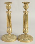 A PAIR OF EMPIRE ORNATE CANDLESTICKS on circular bases. 11ins high.
