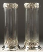 A TALL PAIR OF PLAIN GLASS CIRCULAR VASES with silver bases and rims. 13ins high.