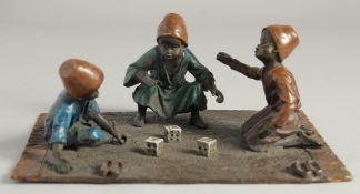 A VIENNA COLD CAST PAINTED GROUP OF THREE BOYS PLAYING DICE on a carpet. 8ins long.