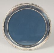 A ROUND SILVER PHOTOGRAPH FRAME with bead edge. 6ins diameter.