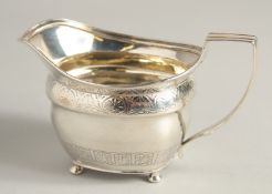 A GEORGE III SILVER CREAM JUG with two bands of atheneum banding, supported on four ball feet.