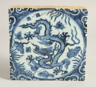A CHINESE BLUE AND WHITE GLAZED TEMPLE TILE, painted with a dragon and lotus. 19.5cm square