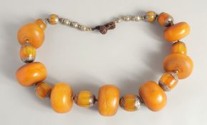 AN ETHNIC LARGE BEADED PRESSED AMBER NECKLACE, with different size beads and metal mounts, largest