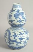 A CHINESE BLUE AND WHITE PORCELAIN DOUBLE GOURD VASE, painted with a dragon and phoenix, 31cm high.