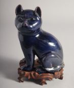 A CHINESE BLUE GLAZED PORCELAIN CAT, on a fitted carved hardwood stand, (repair to one leg), 20.